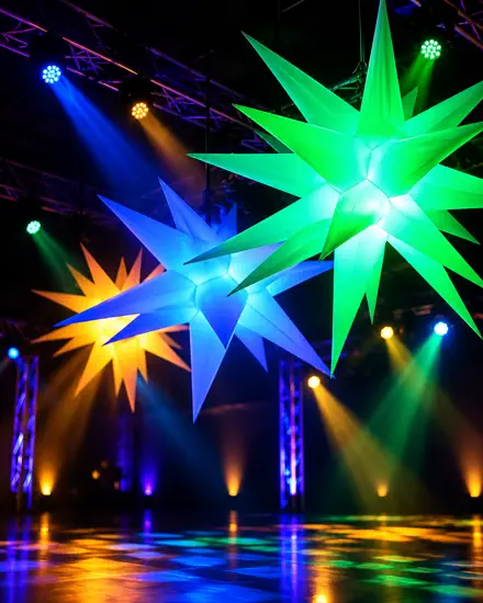 Estrelas infladas gigantes acesas em verde, azul e âmbar, suspensas na treliça sobre a pista