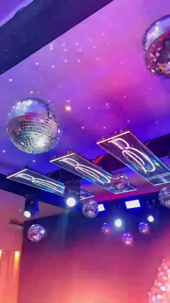Vídeo de uma festa de quinze anos: teto de LED com bolas espelhadas, lustres de cristal e pista iluminada